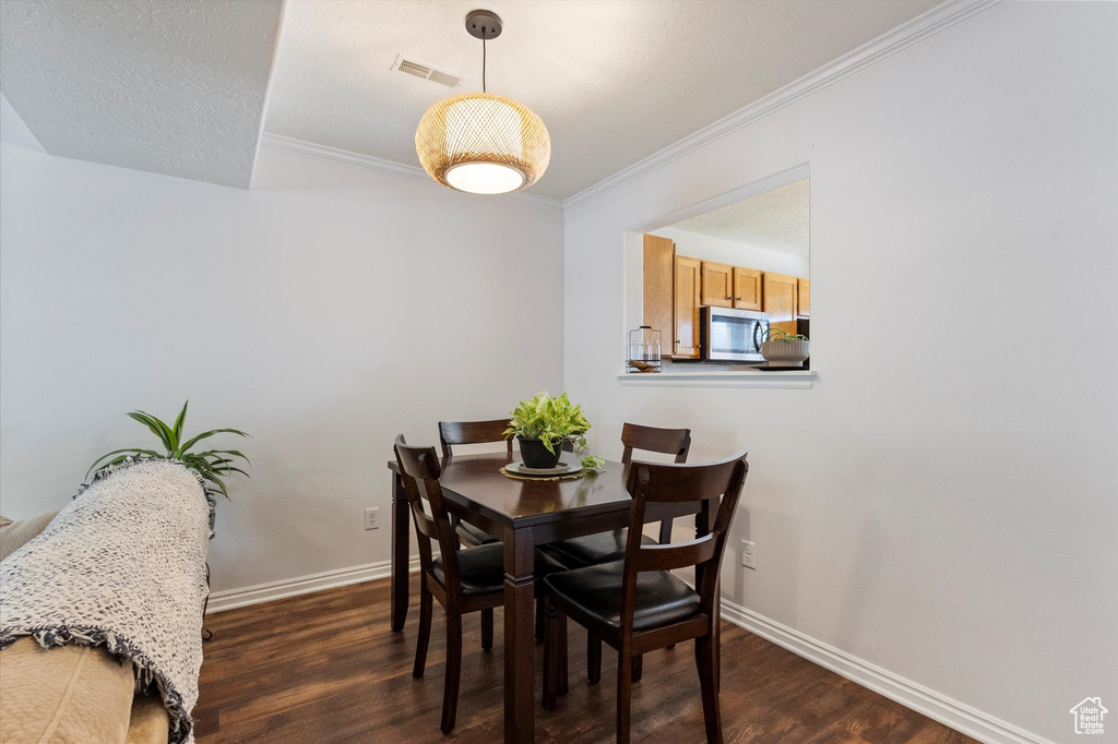 Dining room featuring dark wood finished floors and ornamental molding