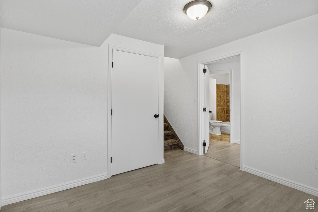 Unfurnished room featuring wood finished floors, stairway, baseboards, and a textured ceiling