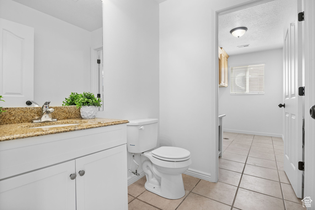Bathroom with toilet, tile patterned floors, vanity, and baseboards