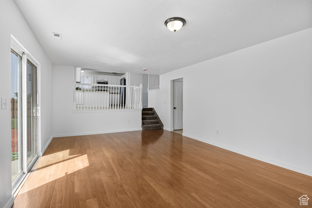 Spare room with stairway, wood finished floors, and baseboards