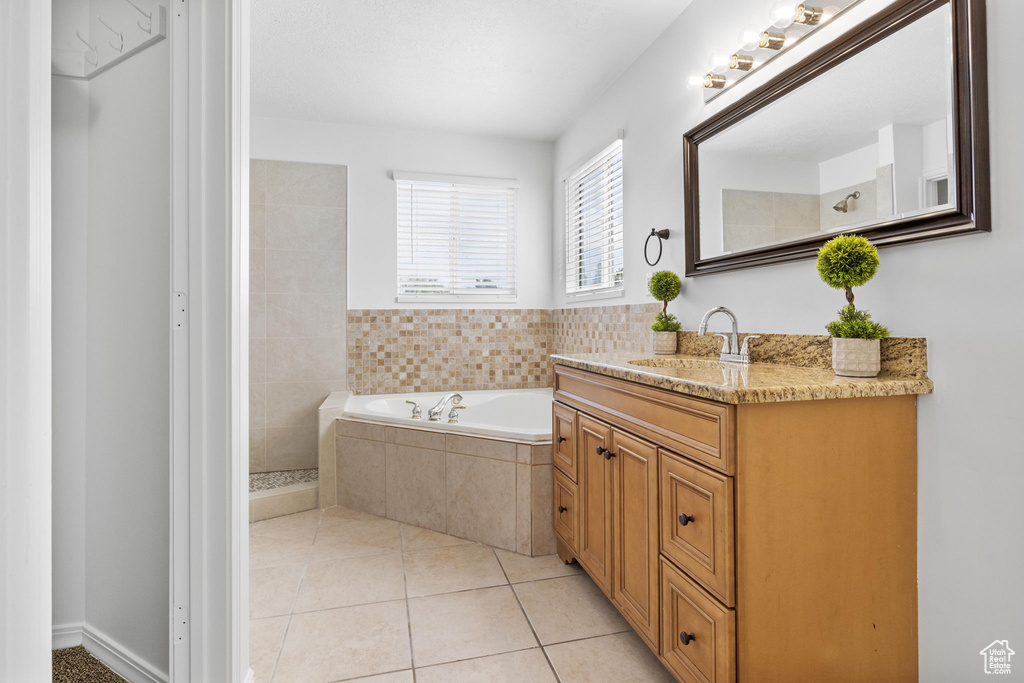 Full bathroom with a bath, vanity, tile patterned floors, and a tile shower