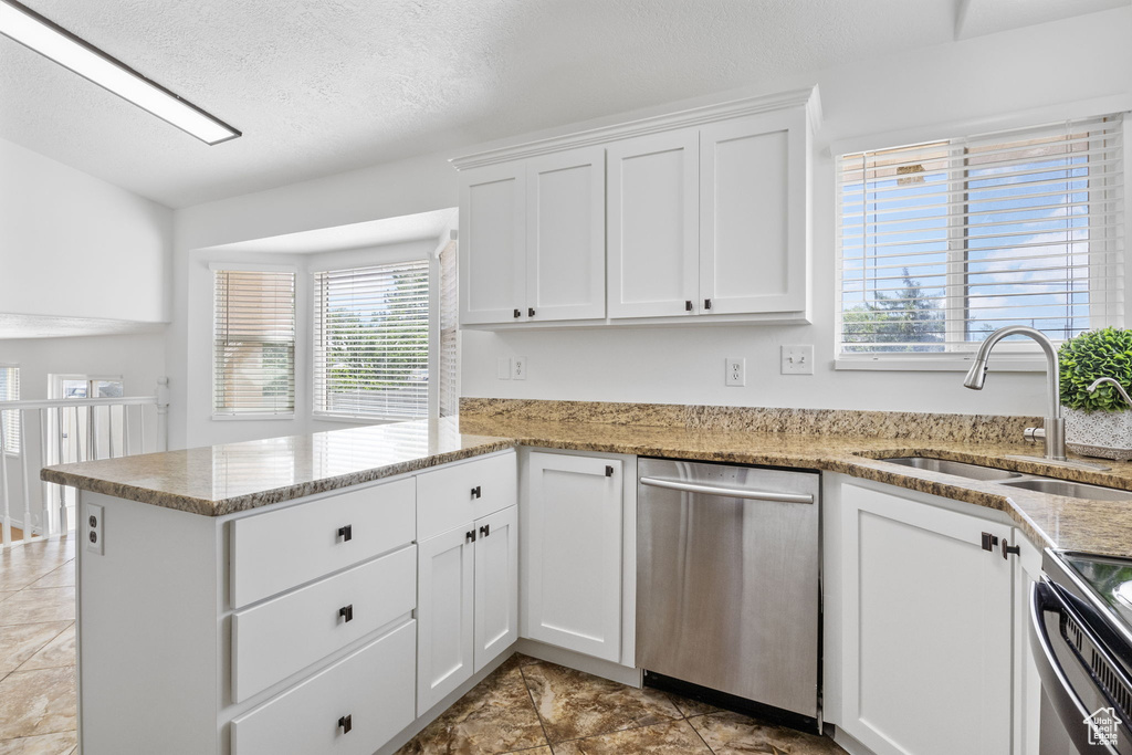 Kitchen featuring dishwasher, a sink, a peninsula, white cabinets, and electric range oven