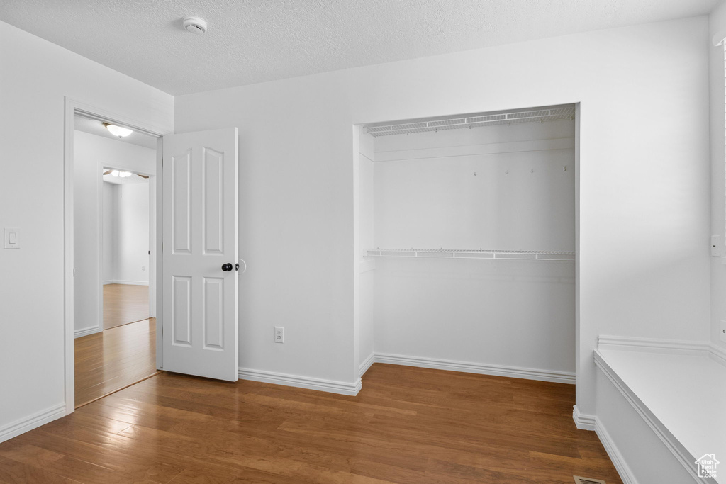 Unfurnished bedroom featuring wood finished floors, a closet, and baseboards
