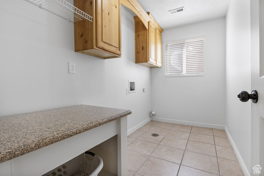 Laundry room featuring hookup for a washing machine, cabinet space, light tile patterned flooring, and baseboards