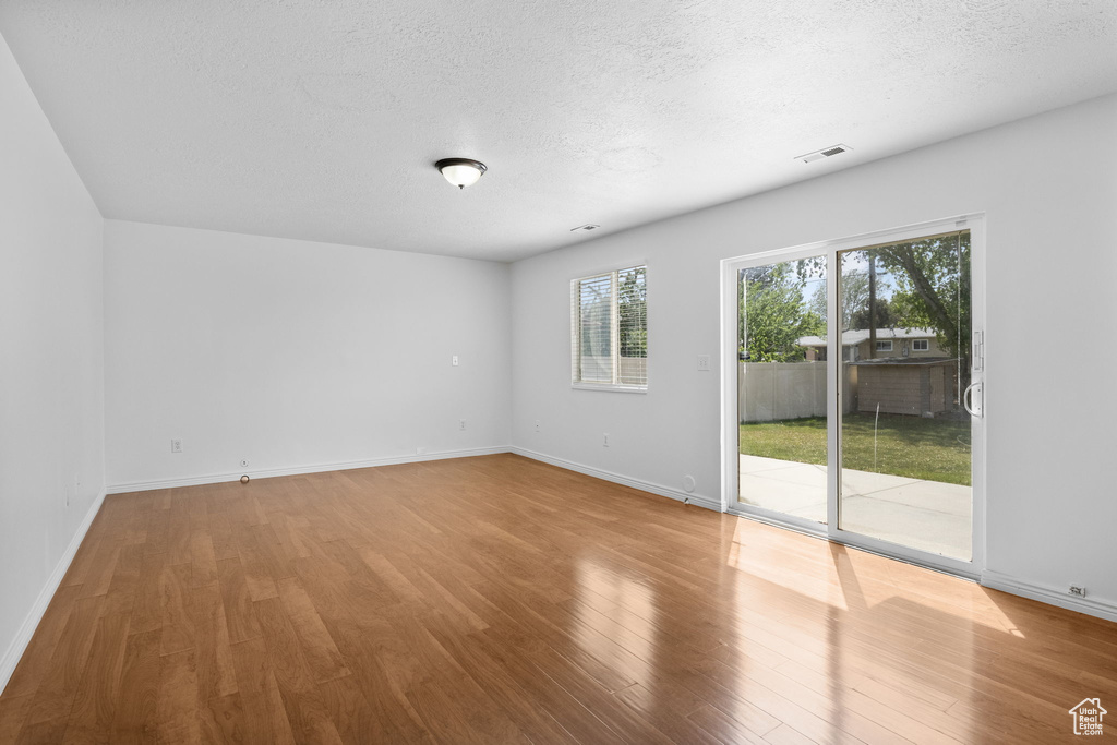 Unfurnished room featuring a textured ceiling, wood finished floors, and baseboards