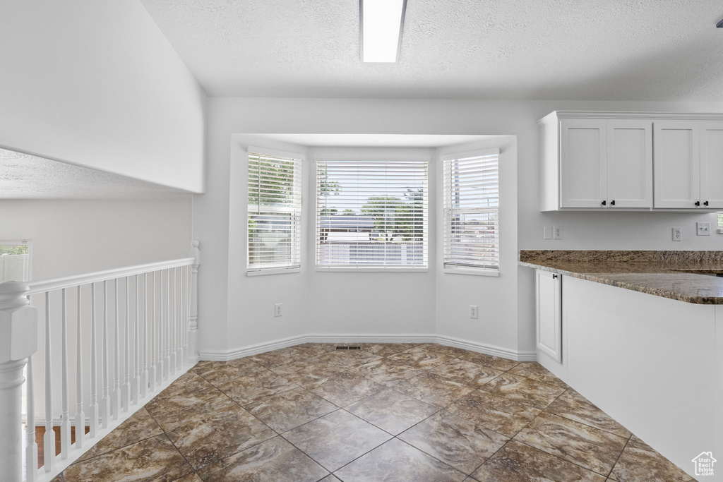 Unfurnished dining area with a textured ceiling and baseboards