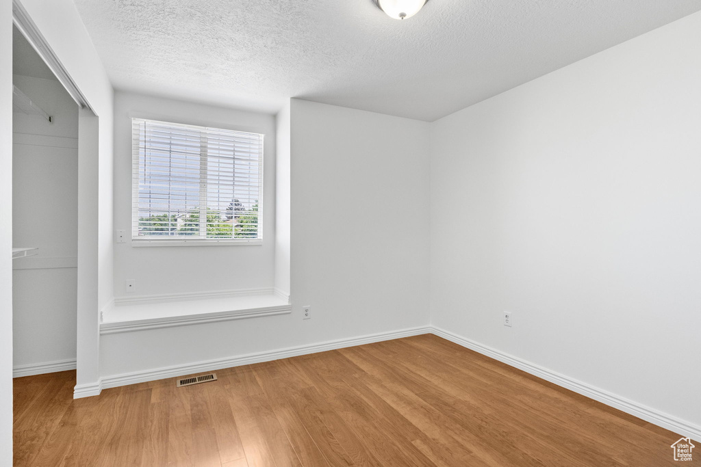 Spare room with wood finished floors, baseboards, and a textured ceiling
