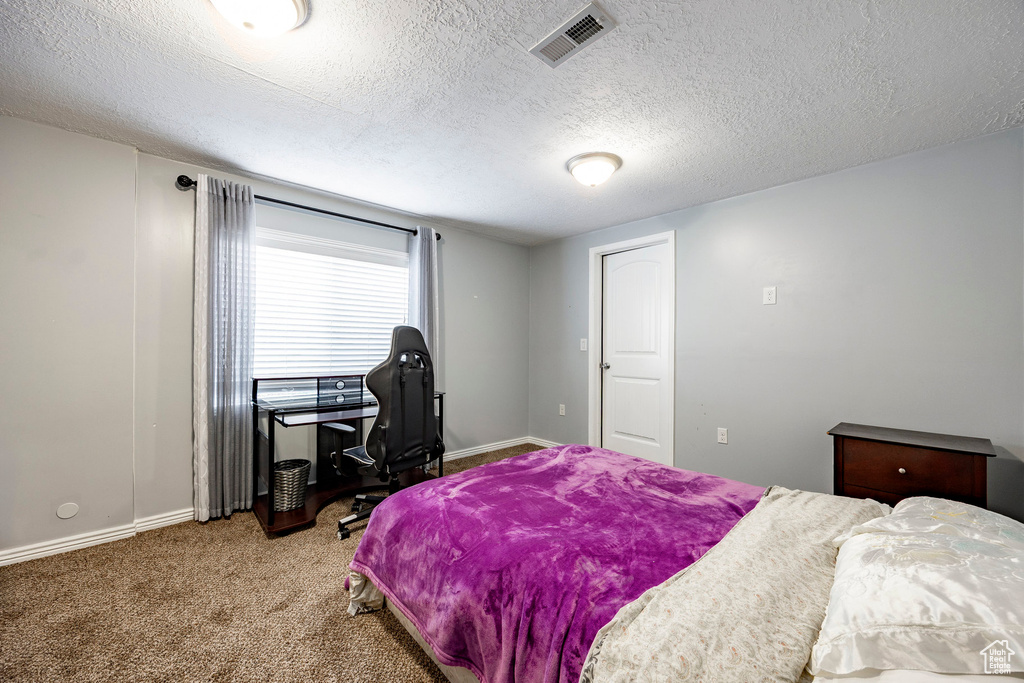 Carpeted bedroom with baseboards, visible vents, and a textured ceiling