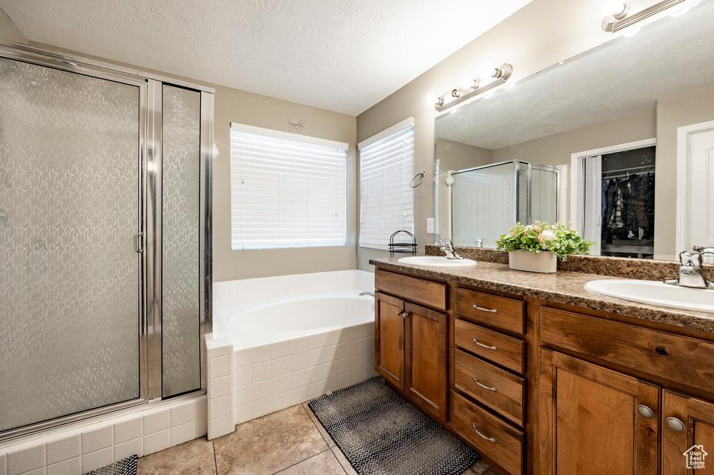 Bathroom featuring a shower stall, tile patterned flooring, a garden tub, and a sink