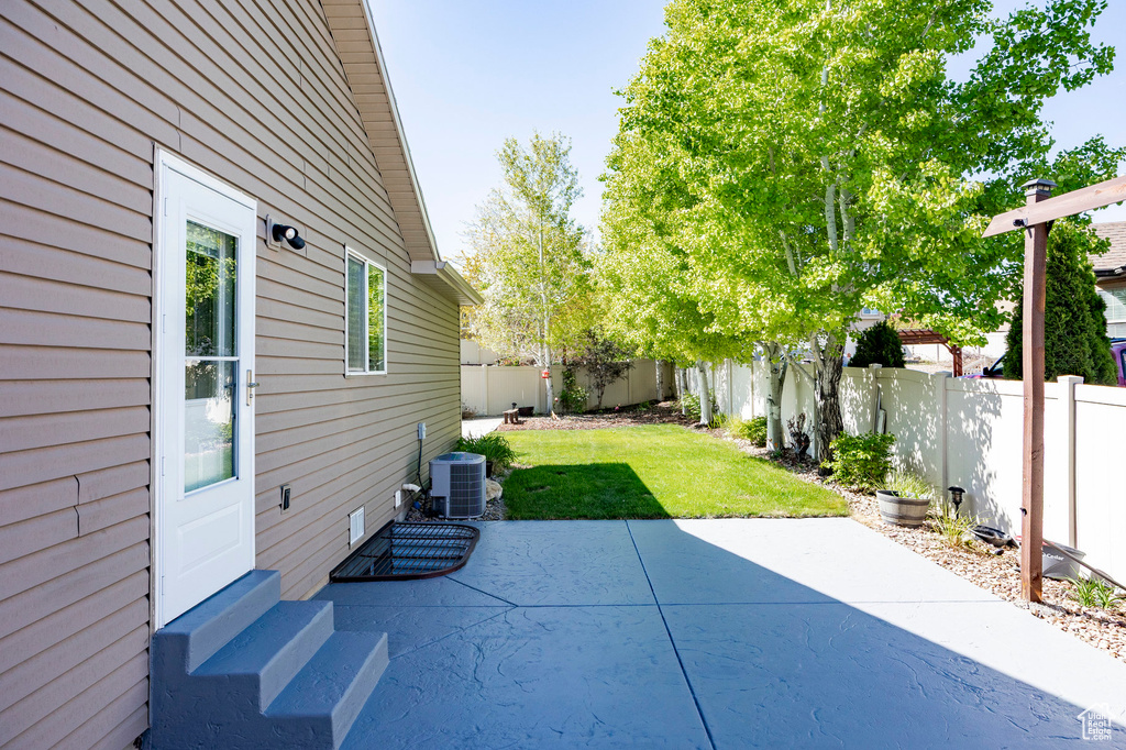 View of patio with central AC unit, entry steps, and a fenced backyard