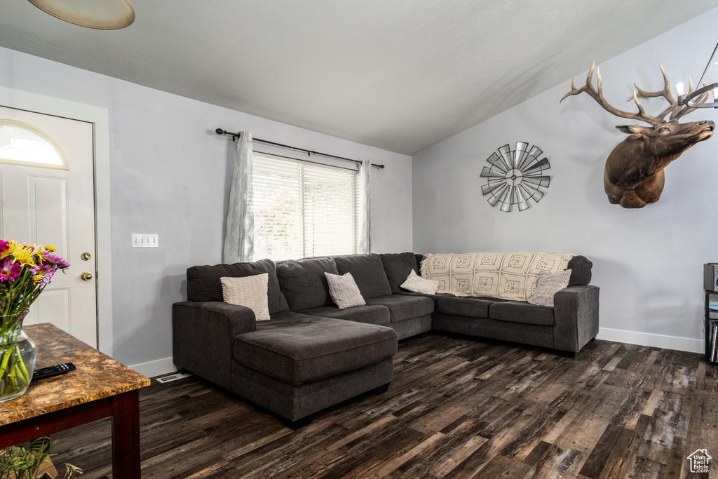 Living room with vaulted ceiling, dark wood-style flooring, and baseboards
