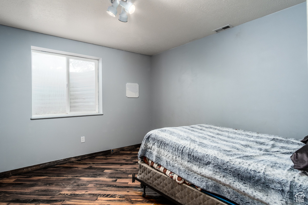 Bedroom with dark wood-style flooring and baseboards