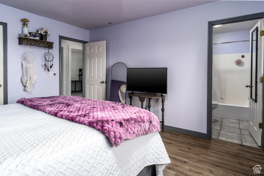 Bedroom featuring wood finished floors, baseboards, and connected bathroom