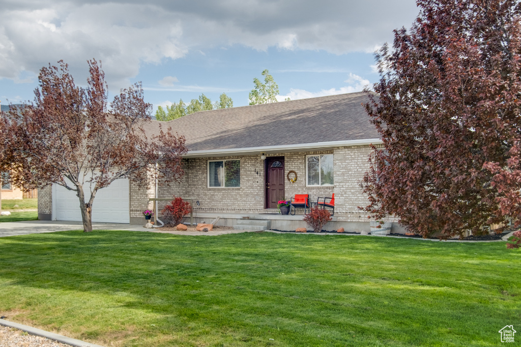Ranch-style house with brick siding, a shingled roof, a garage, driveway, and a front lawn