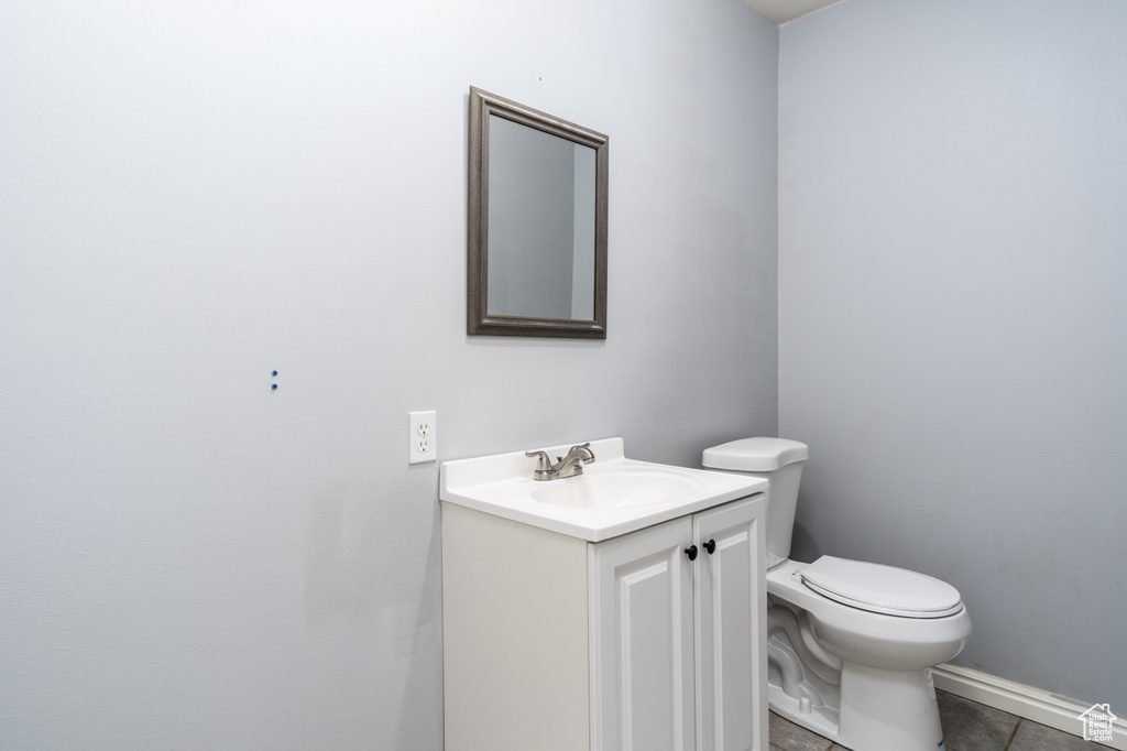 Half bathroom with vanity, toilet, and tile patterned floors