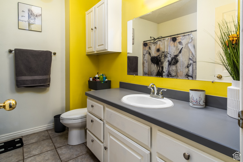 Bathroom featuring toilet, vanity, tile patterned floors, baseboards, and a shower with shower curtain