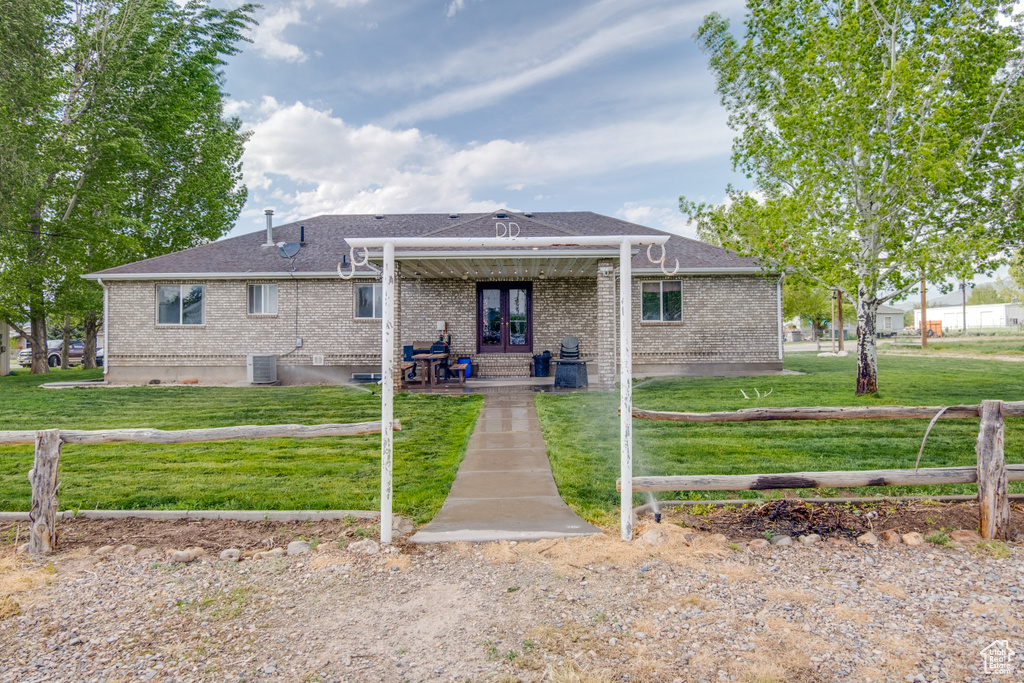 View of front of property with a front yard, a patio area, cooling unit, and brick siding
