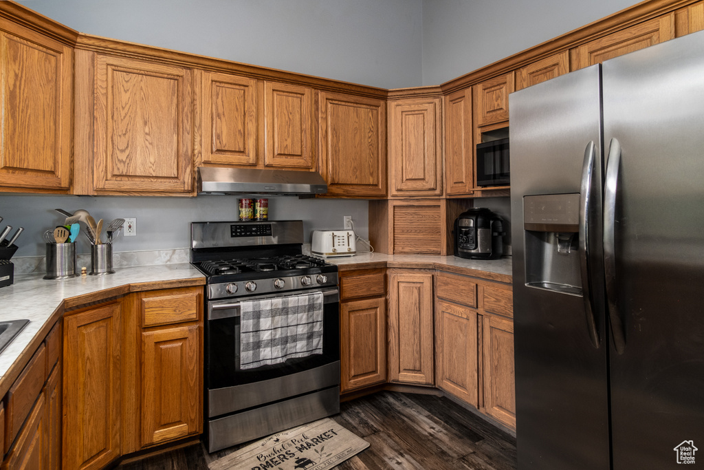 Kitchen featuring stainless steel appliances, wall chimney range hood, and brown cabinetry