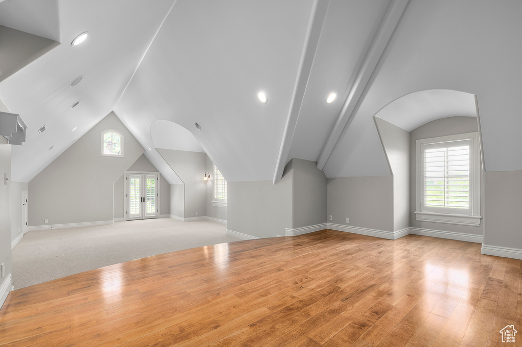 Additional living space featuring vaulted ceiling, light wood-style floors, and baseboards