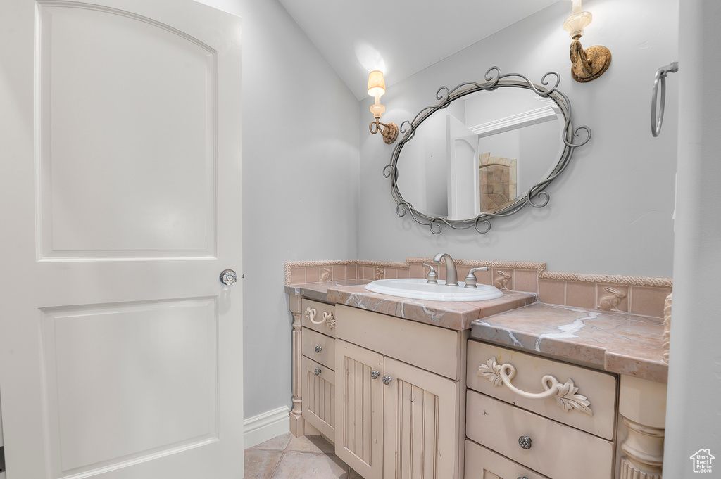 Bathroom featuring vanity, baseboards, and vaulted ceiling