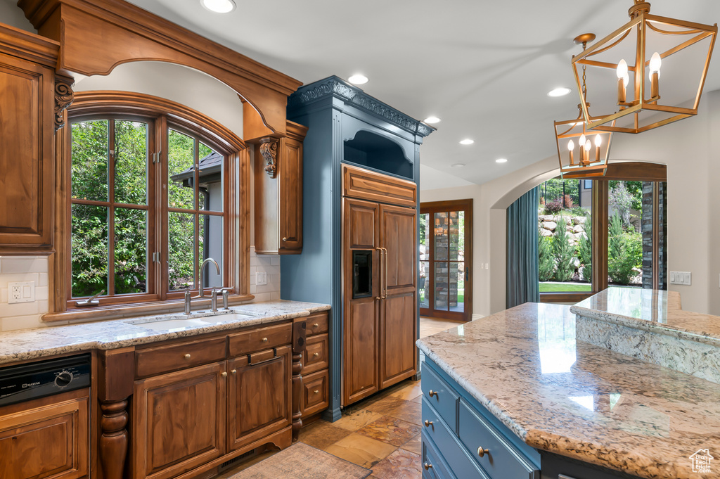Kitchen with a sink, recessed lighting, decorative backsplash, a chandelier, and light stone counters
