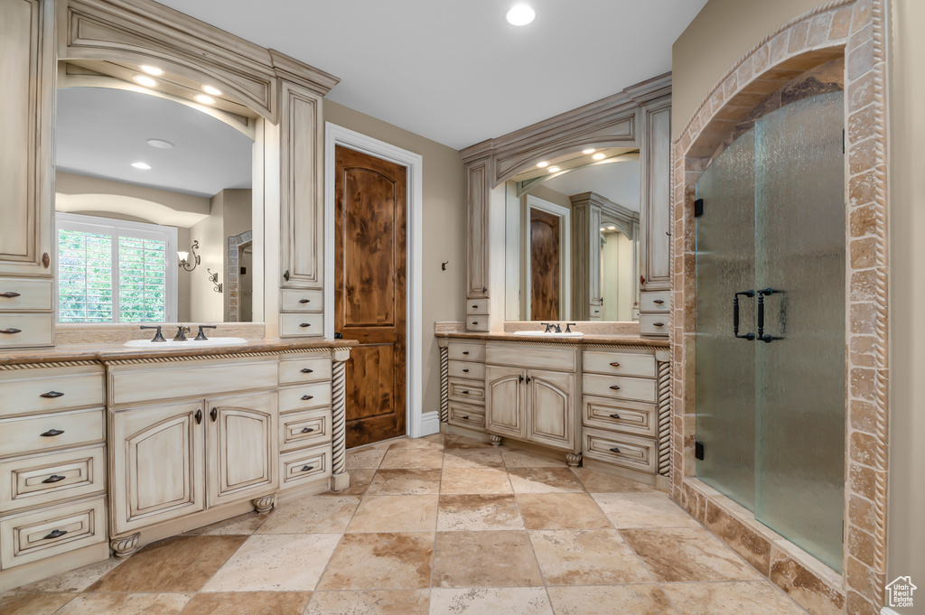Bathroom featuring a shower stall, two vanities, stone finish flooring, recessed lighting, and baseboards