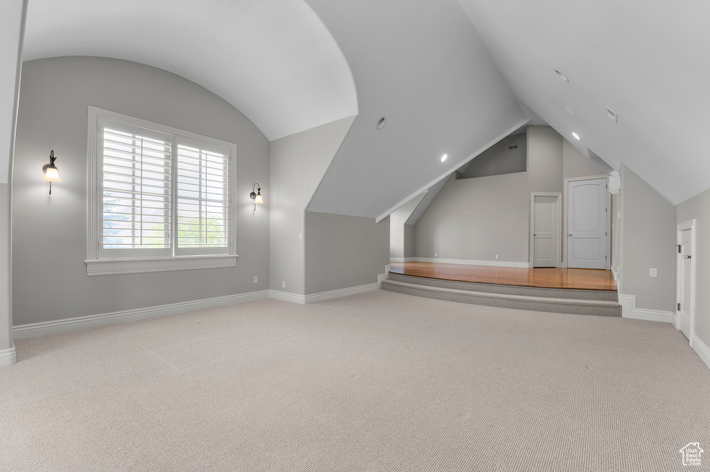 Additional living space featuring vaulted ceiling, carpet flooring, and baseboards