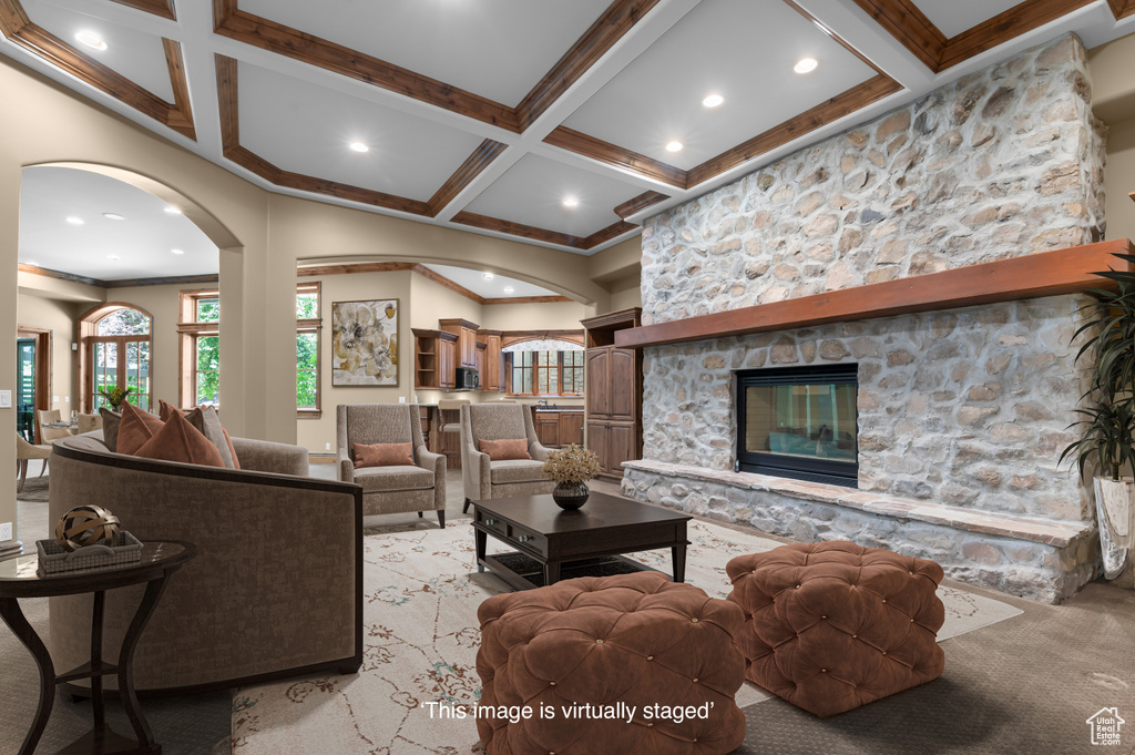 Living area with coffered ceiling, arched walkways, light colored carpet, beam ceiling, and crown molding