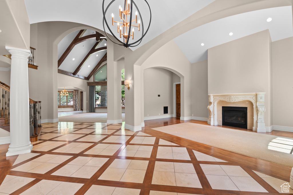 Entrance foyer with a high end fireplace, high vaulted ceiling, inlaid floor details, recessed lighting, and a chandelier