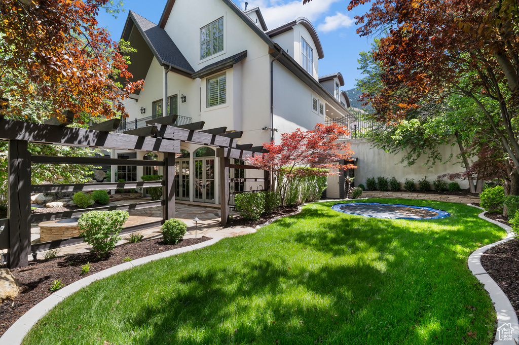 Rear view of property featuring stucco siding and a pergola
