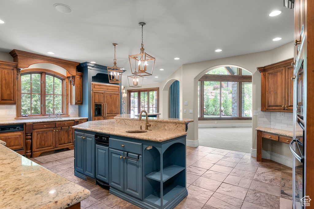 Kitchen with a sink, backsplash, baseboards, an island with sink, and recessed lighting