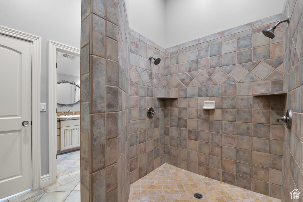 Full bathroom with a tile shower, vanity, and tile patterned floors