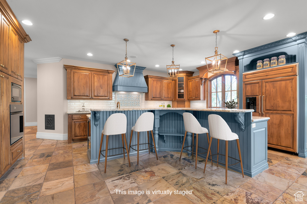 Kitchen with custom exhaust hood, built in appliances, recessed lighting, baseboards, and a breakfast bar