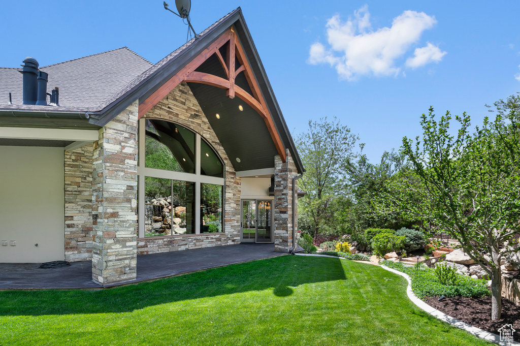View of side of home featuring stone siding and a lawn