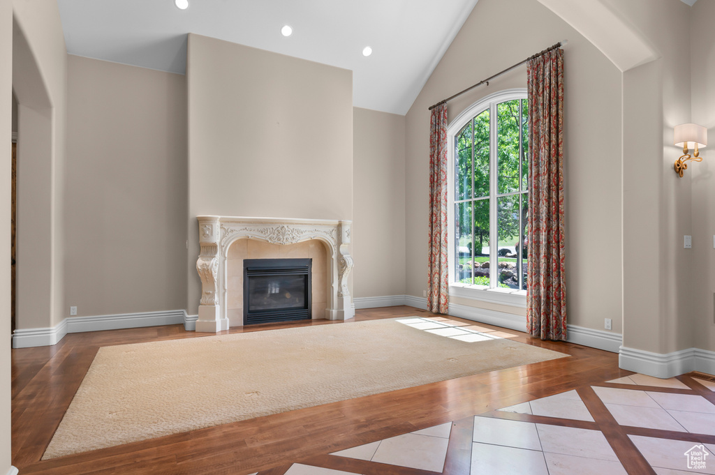 Unfurnished living room with baseboards, a high end fireplace, recessed lighting, inlaid floor details, and lofted ceiling