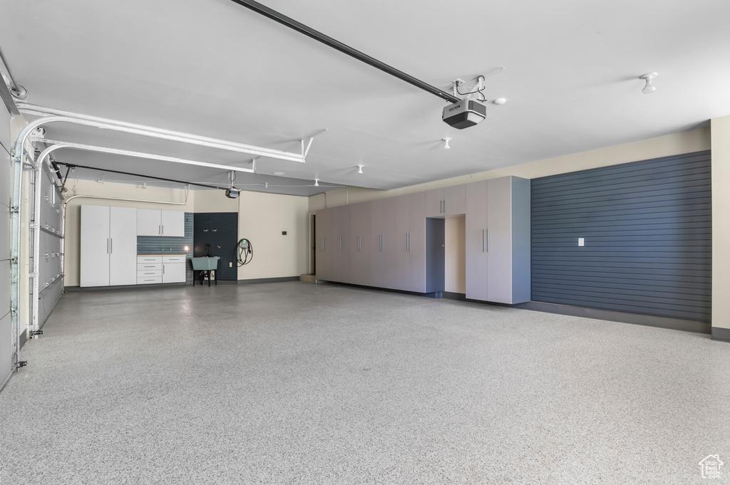 Garage featuring a garage door opener, baseboards, and a sink