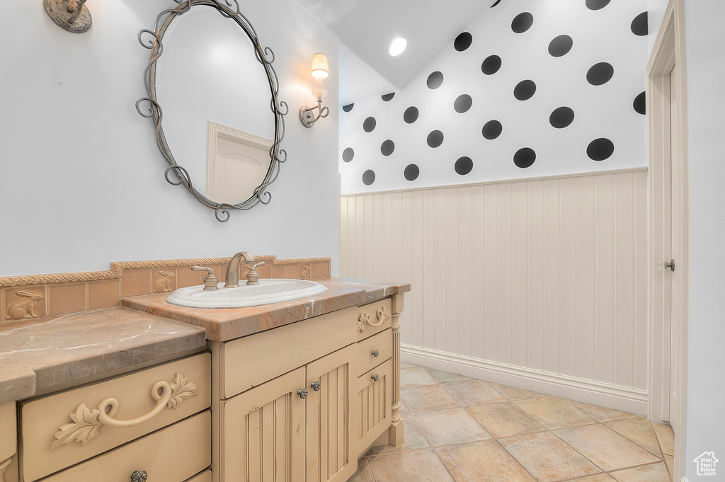 Bathroom with wallpapered walls, vanity, wainscoting, and baseboards