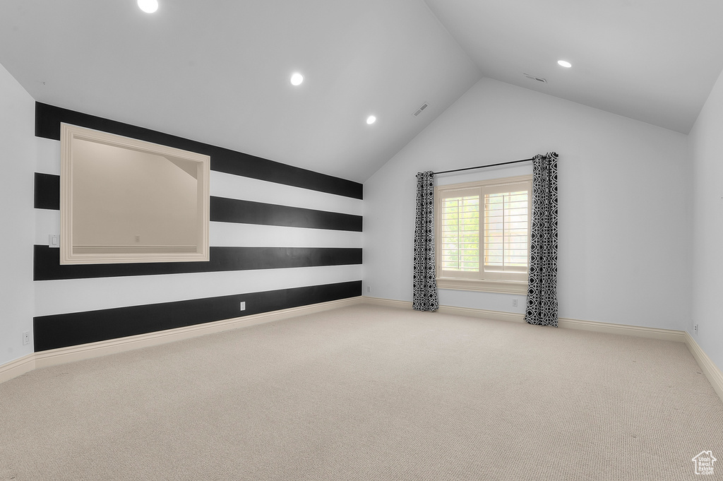 Spare room featuring vaulted ceiling, recessed lighting, carpet, and baseboards