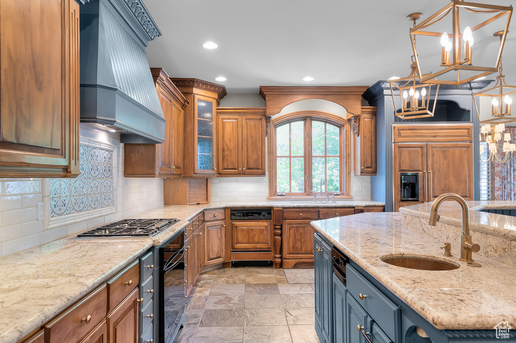 Kitchen with custom exhaust hood, stainless steel gas cooktop, a chandelier, a sink, and oven