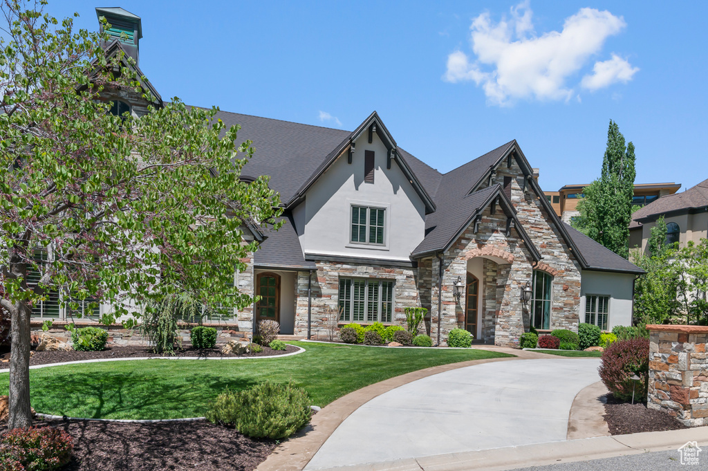 View of front of property featuring stone siding, stucco siding, and a front yard
