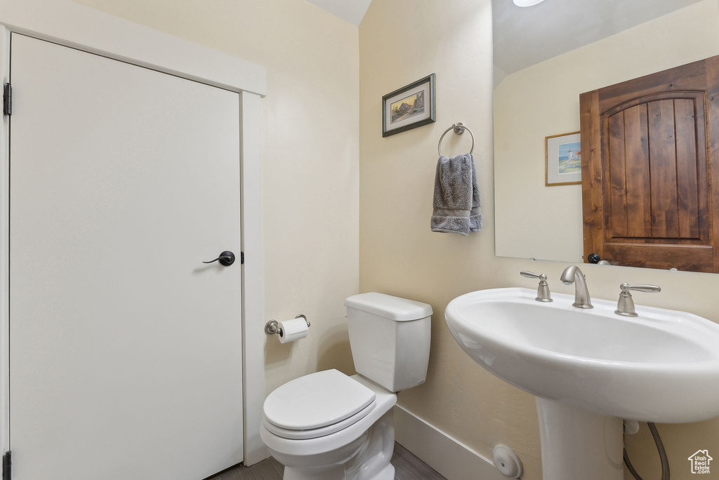 Half bath featuring toilet, a sink, and baseboards