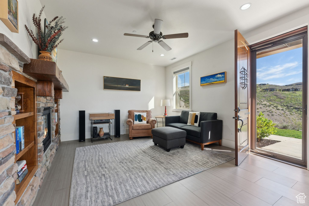 Living area featuring a stone fireplace, ceiling fan, recessed lighting, and wood finished floors