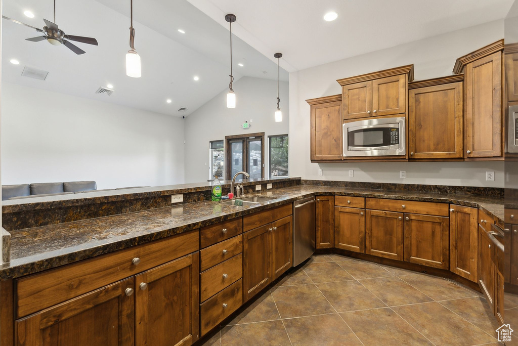 Kitchen with stainless steel appliances, a sink, dark tile patterned floors, pendant lighting, and ceiling fan