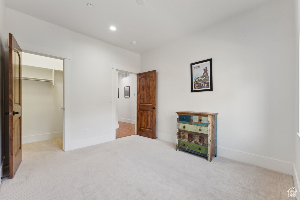 Unfurnished bedroom with carpet flooring, baseboards, a walk in closet, recessed lighting, and a closet
