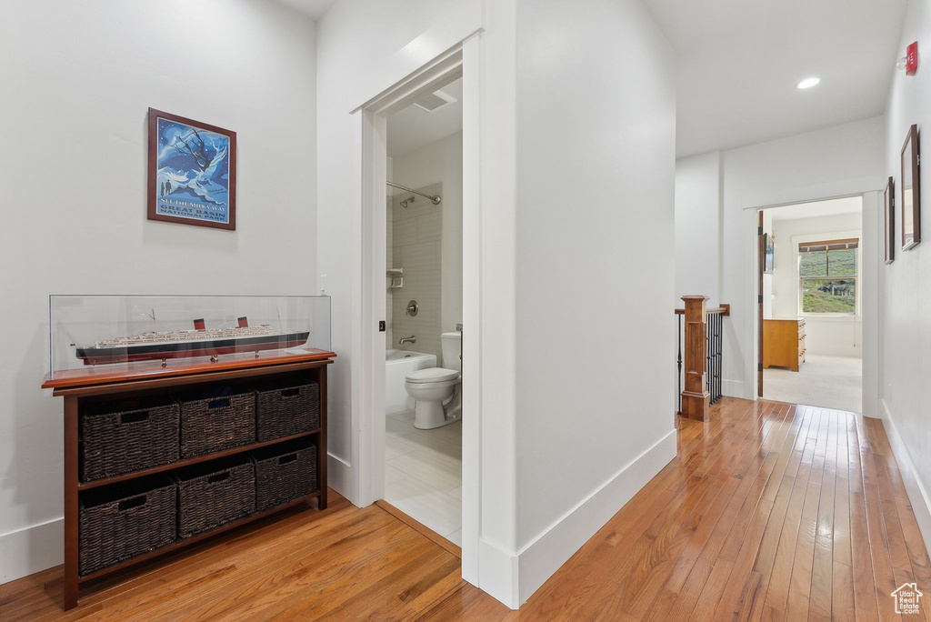Hallway with wood-type flooring, an upstairs landing, baseboards, and recessed lighting