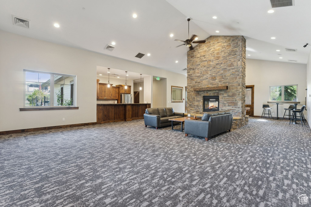 Living room featuring carpet floors, ceiling fan, high vaulted ceiling, a fireplace, and baseboards