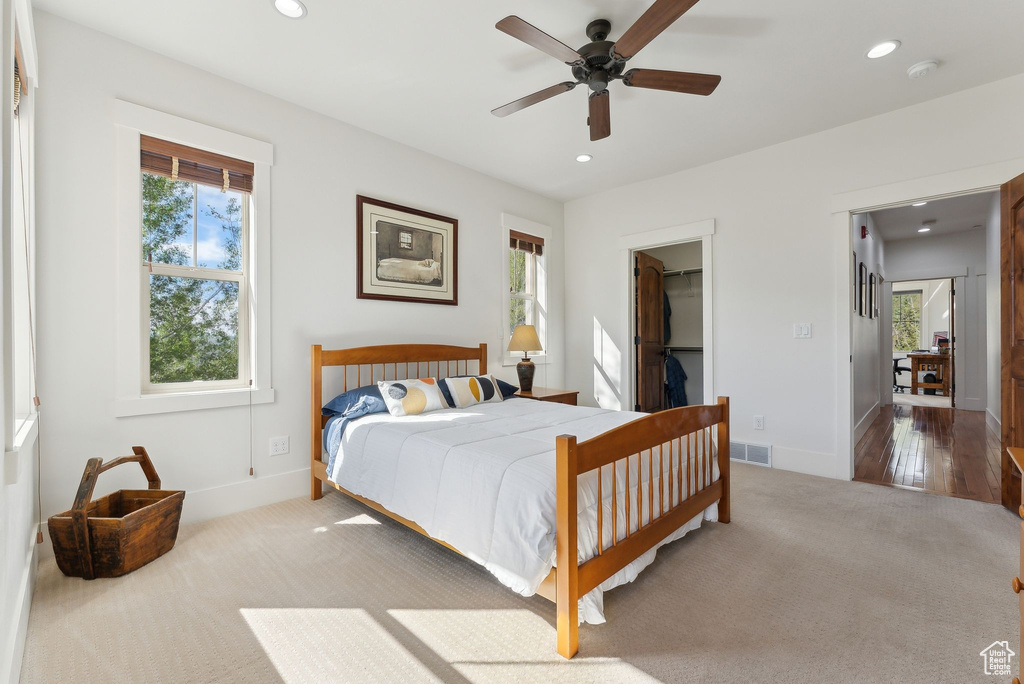 Bedroom featuring carpet floors, recessed lighting, multiple windows, baseboards, and a walk in closet