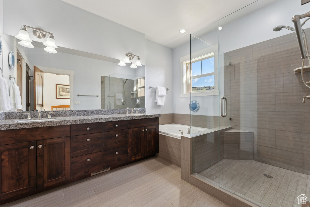 Bathroom featuring a stall shower, a bath, and double vanity