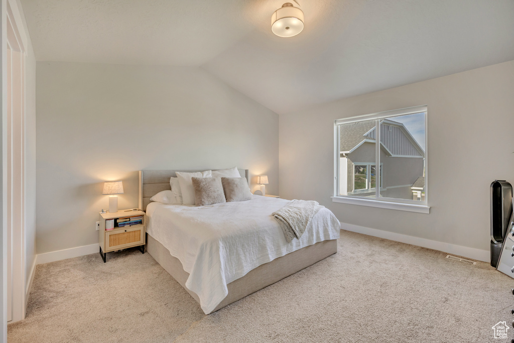 Bedroom featuring lofted ceiling, light carpet, and baseboards
