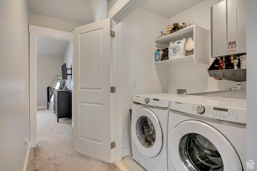 Clothes washing area with washing machine and clothes dryer, water heater, and light colored carpet